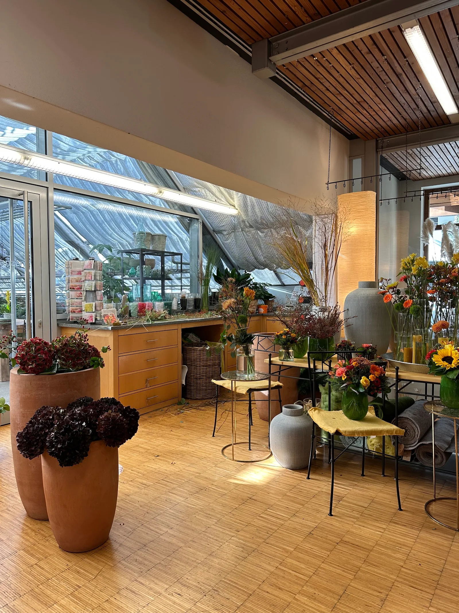Verkaufsraum mit Holzboden, Terrakotta-Gefäßen und Sträußen